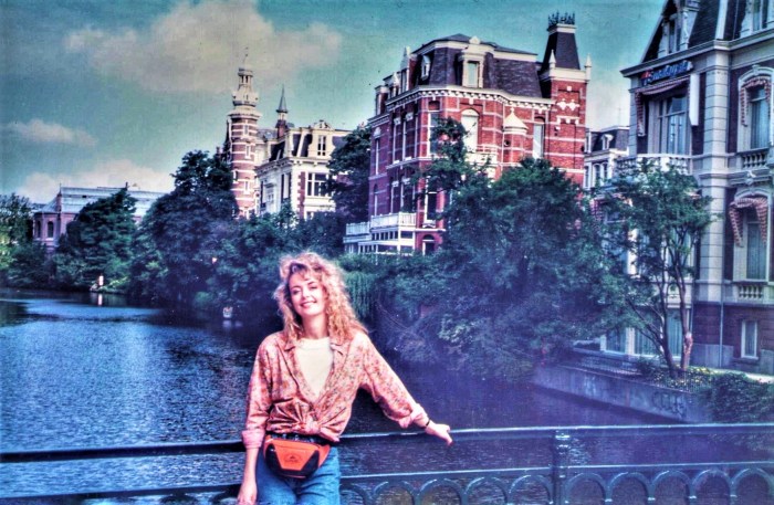 me standing in the sun leaning on a bridge over the canal in Amsterdam